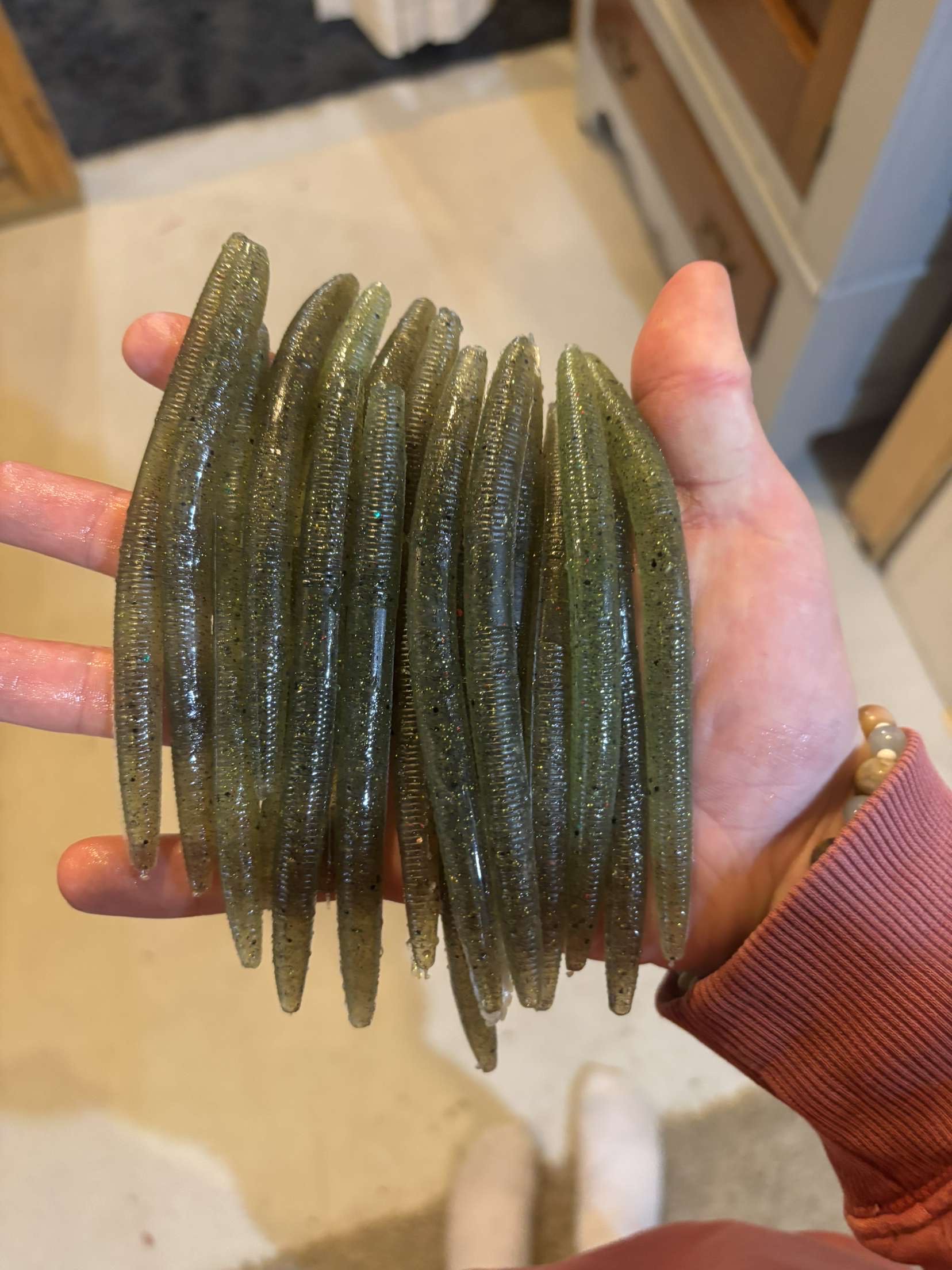 A close-up of a brown crayfish on a rock in shallow, clear water, with rocks scattered below.